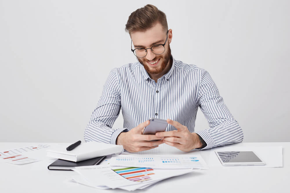 Agência Simi homem-estiloso-com-mensagens-de-penteados-da-moda-no-smartphone