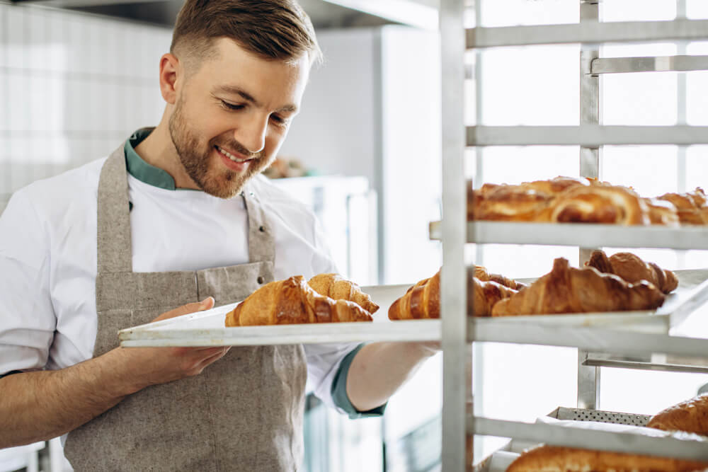 padeiro-de-homem-segurando-croissants-na-padaria agencia simi